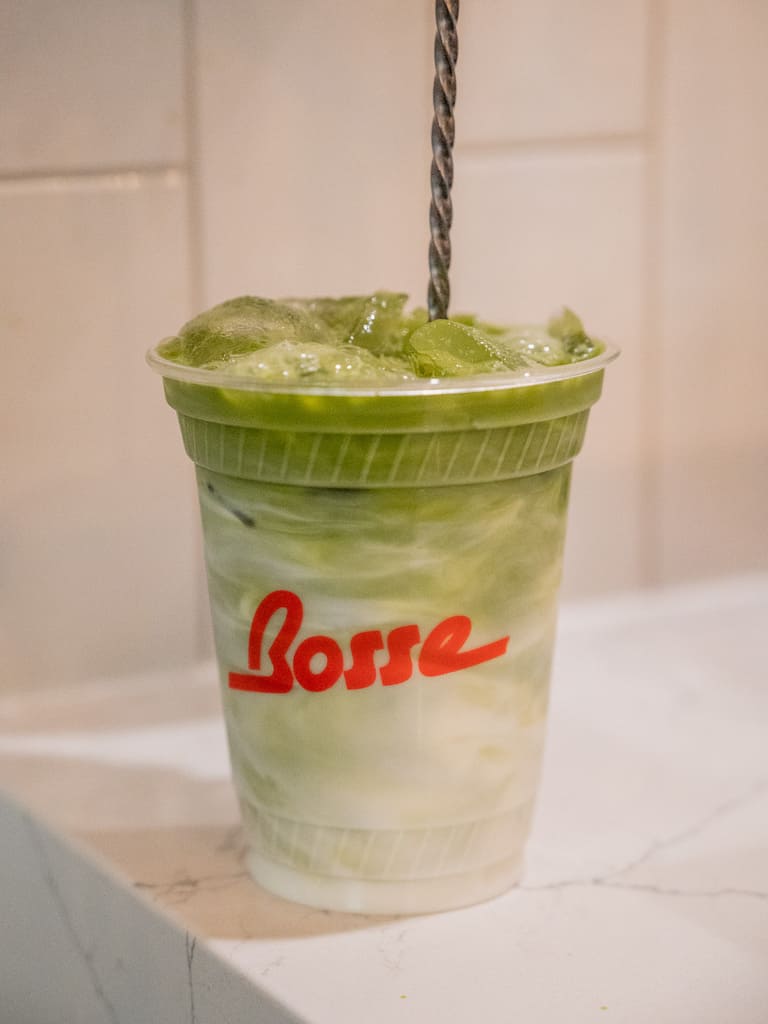 Iced matcha latte in a Bosse Café cup on a marble countertop