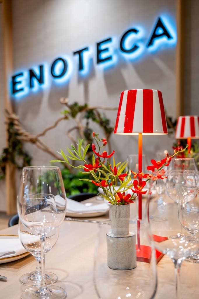 Close-up of table setting at Enoteca with red striped lamp and wine glasses.