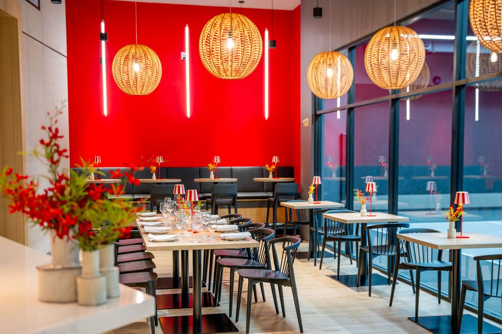 Bright red and wood-toned dining room at Enoteca with striped lamps and round wicker lights.
