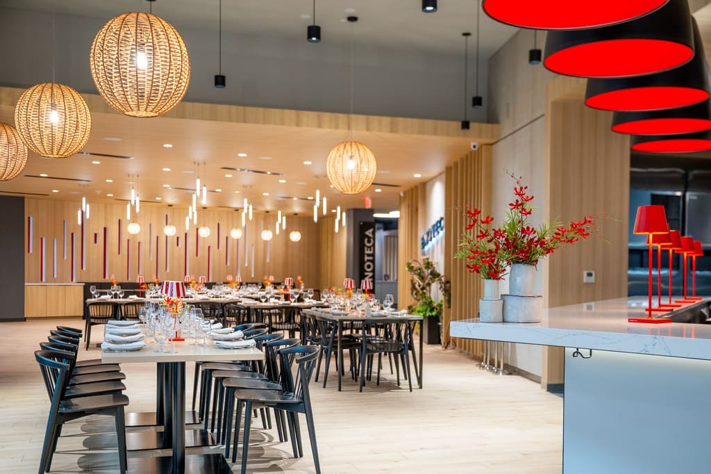 Wide view of Enoteca dining area with modern lighting, wood finishes, and red lamps.