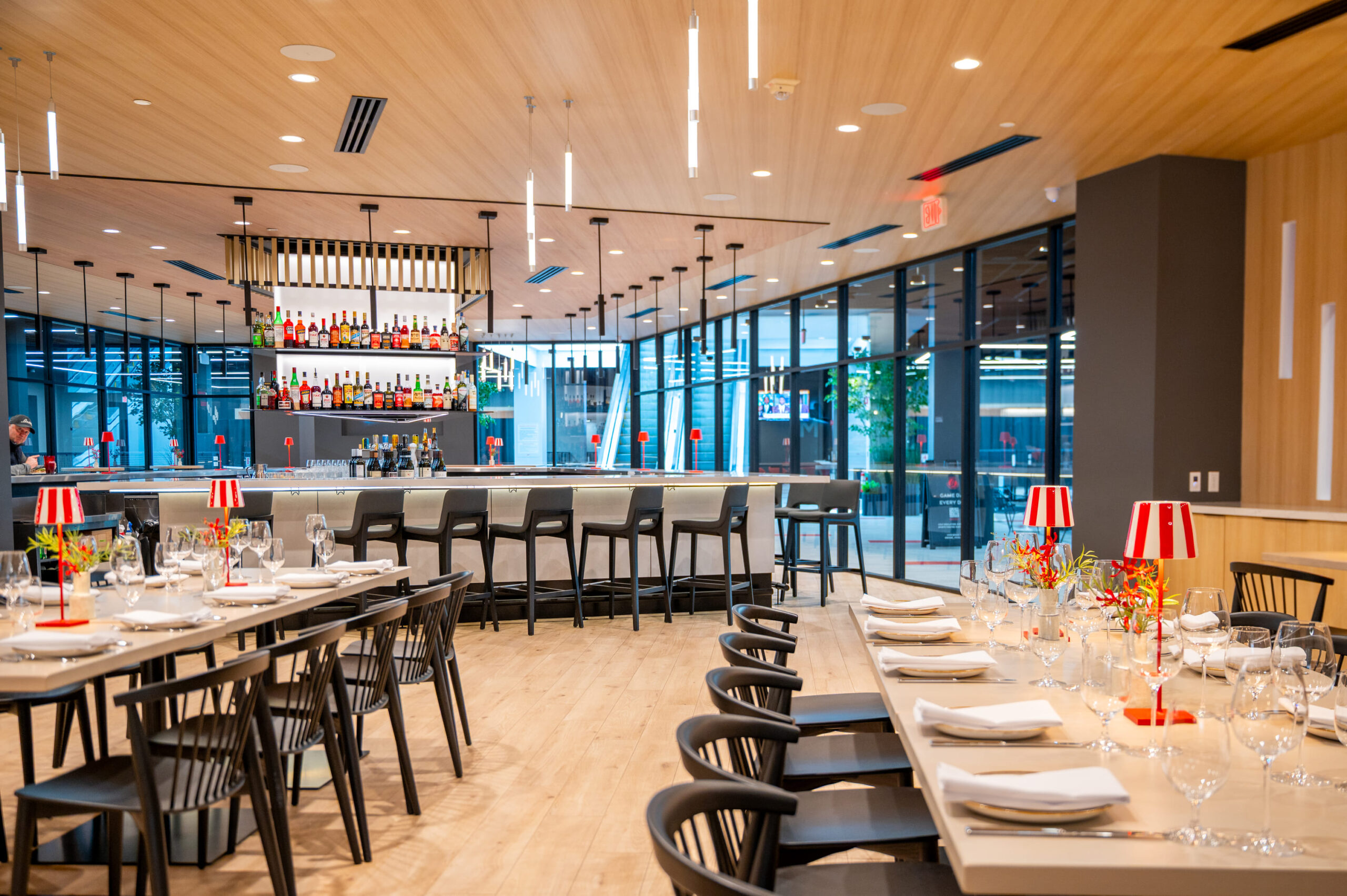 Contemporary restaurant bar with high chairs, liquor display, and elegant table settings.