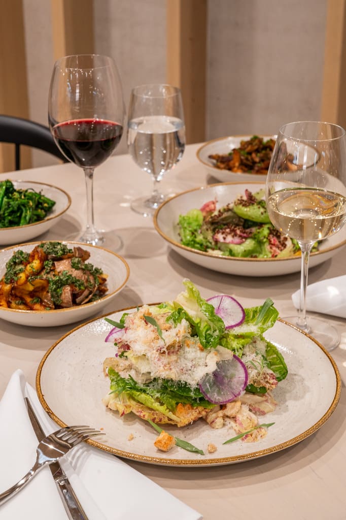 Table with multiple Italian dishes and wine glasses at Enoteca.