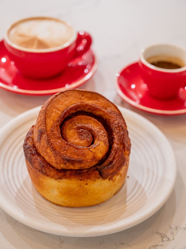 Cinnamon roll served with espresso and cappuccino in red cups