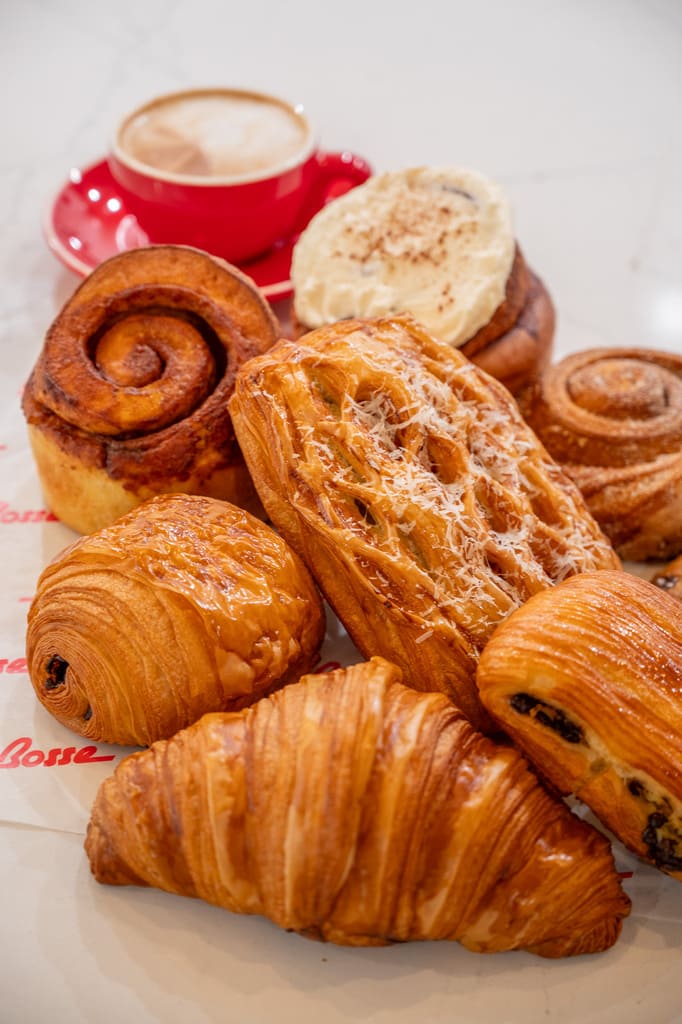Variety of pastries and cinnamon rolls with cappuccino in red cup