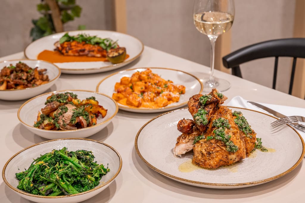 Herb-roasted chicken with Italian sides and a glass of white wine on a modern dining table