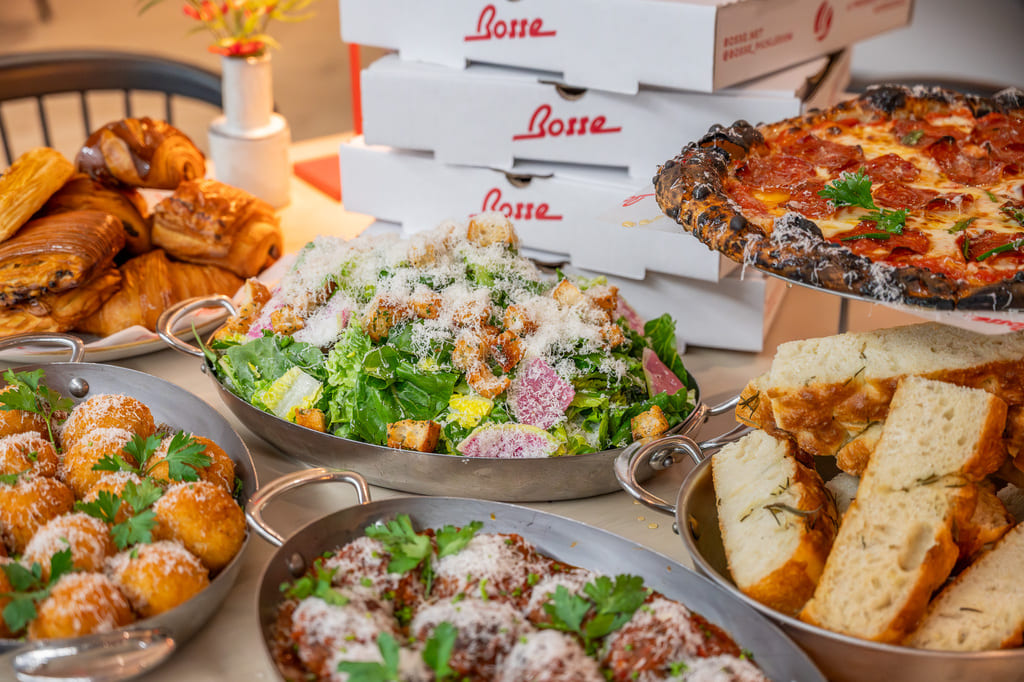 Table spread with pizza, Caesar salad, focaccia, and pastries