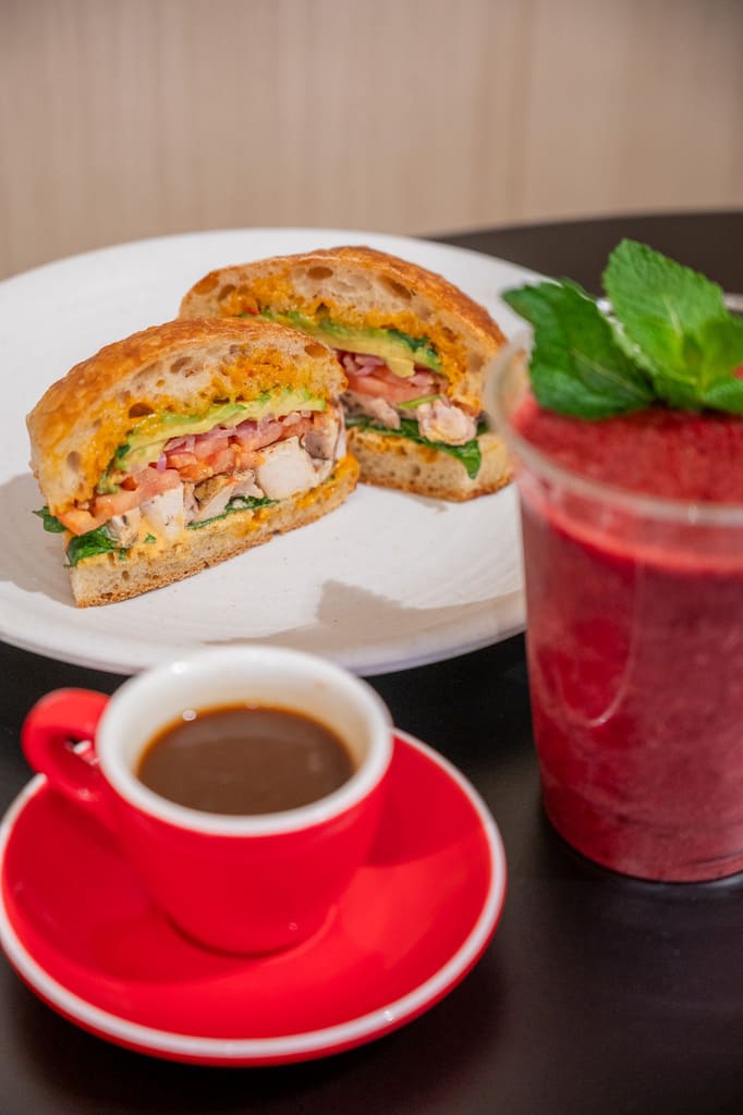 Sliced chicken sandwich with espresso and berry smoothie